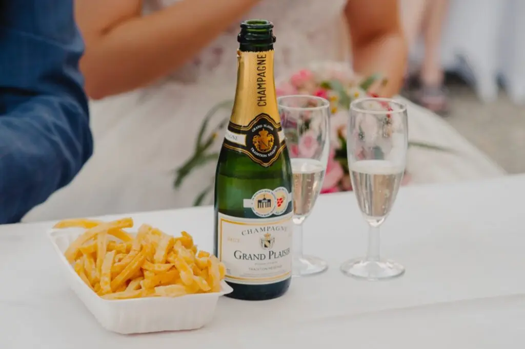 Schale mit Pommes frites, Champagner und zwei Champagnergläsern